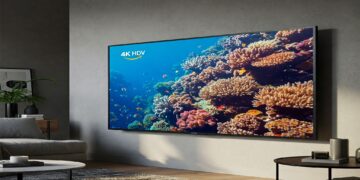 A modern living room with an Amazon Fire TV 4-Series mounted on the wall, displaying a vibrant underwater scene.