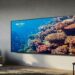 A modern living room with an Amazon Fire TV 4-Series mounted on the wall, displaying a vibrant underwater scene.