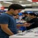 Shoppers looking at electronics in a store, suggesting potential price increases due to tariffs.